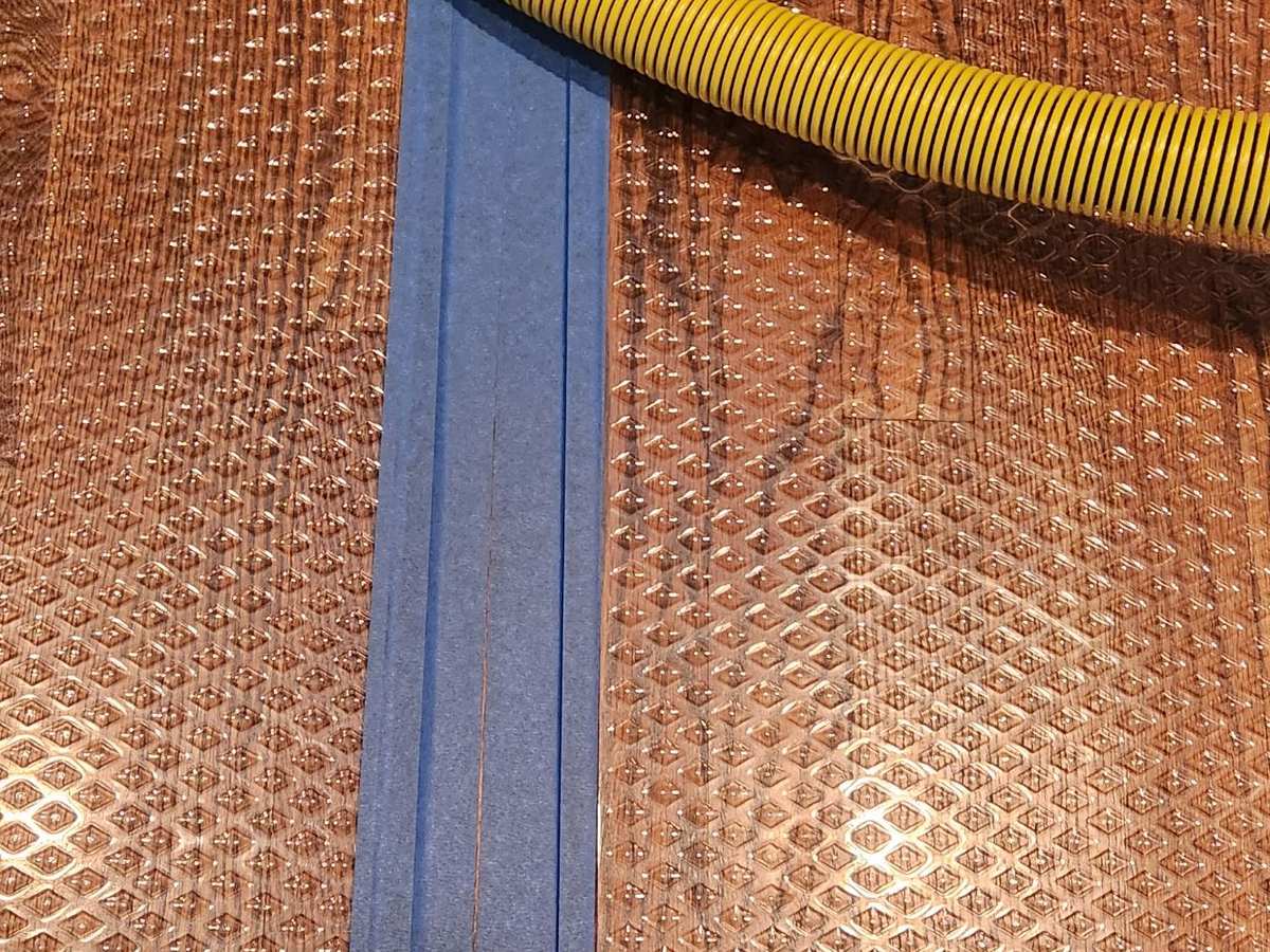 Close-up of drying panels taped to wet hardwood flooring to pull moisture out of the boards