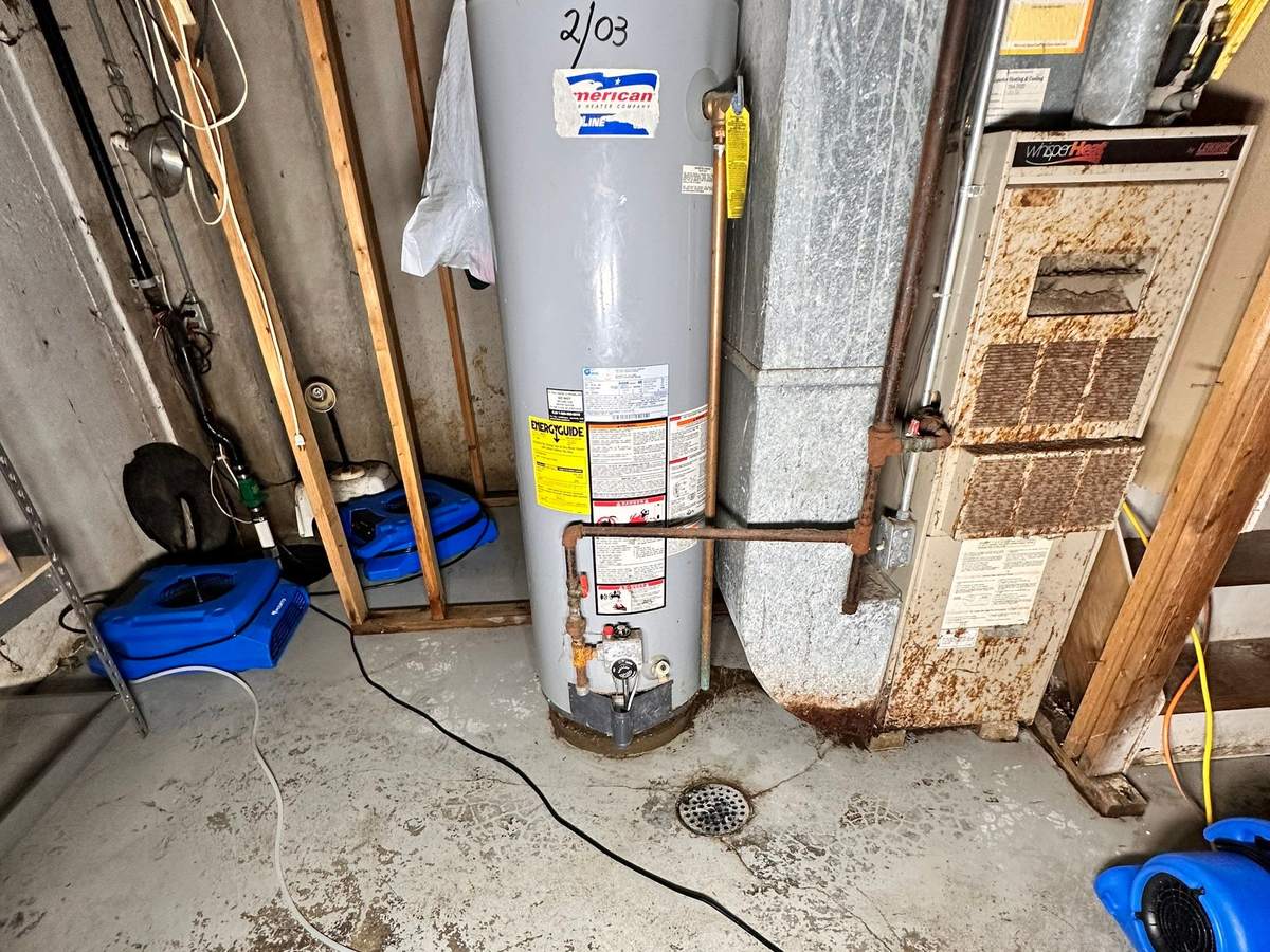 Air movers drying a basement floor around a gas water heater and furnace
