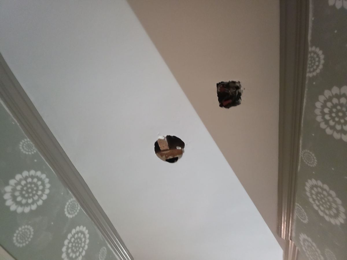 Small inspection and drying holes cut in a ceiling below a bathroom leak in Roeland Park, KS