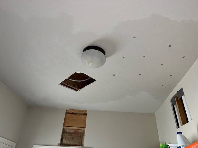 Ceiling drywall cut out around a water stain below a failed upstairs supply line in Lee’s Summit, MO