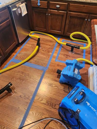 Floor-mat drying system with hoses and a dehumidifier drying cupped hardwood floors in an Overland Park, KS kitchen