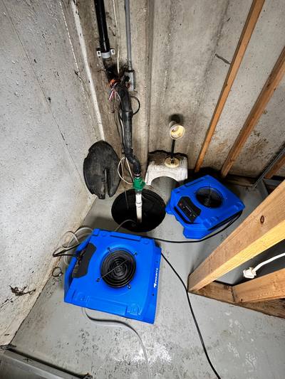 Air movers drying a basement floor next to the sump pit in Prairie Village, KS