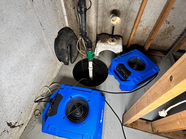 Air movers drying a basement floor near the sump pit in Prairie Village, KS