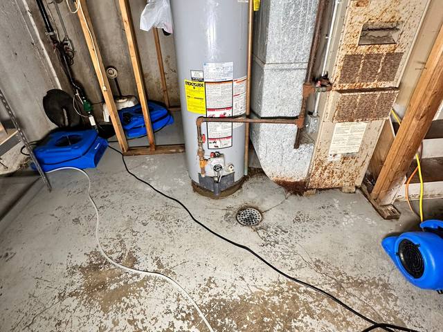 Air movers drying a basement floor beside a water heater in Prairie Village, KS